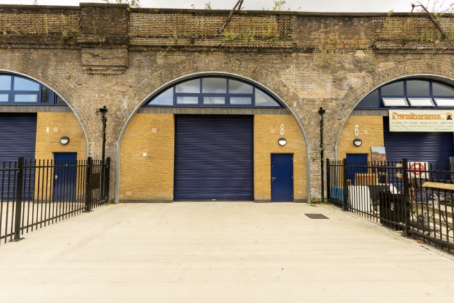 The front of an arch, with high level glazing, a closed electric roller shutter entrance big enough for vehicle access, and a pedestrian door.