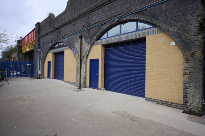 The front of an arch with a closed electric roller shutter entrance big enough for vehicle access.