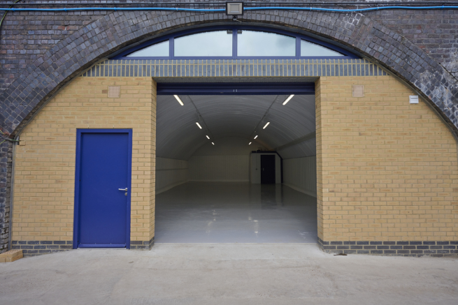 The front of an arch, with high level glazing, an open electric roller shutter entrance big enough for vehicle access, and a pedestrian door.