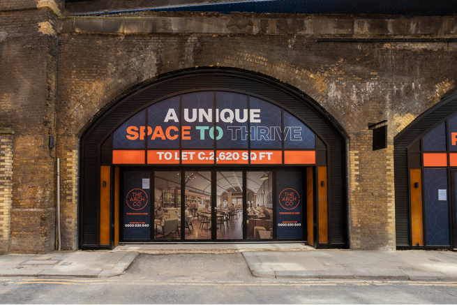 The front of an arch, with a fully glazed frontage and door allowing you to see into the arch interior.