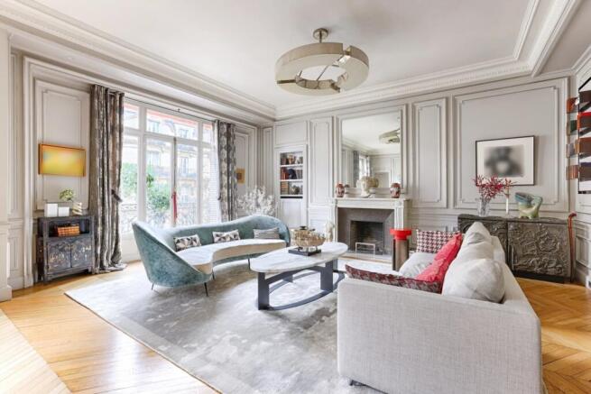 Elegant living room with a classic design, featuring stylish furniture, a fireplace, and large windows with curtains.