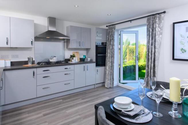 Open-plan kitchen/diner with integrated appliances and French doors leading onto garden in Ingleby s