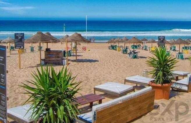 Sunny beach with lounge chairs, umbrellas, calm at