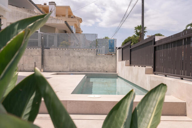L-shaped pool hidden behind the fence by the street entrance