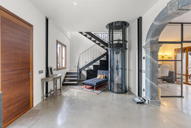 Eleganter Eingangsbereich mit modernem Pneumatik-Aufzug und Treppenaufgang