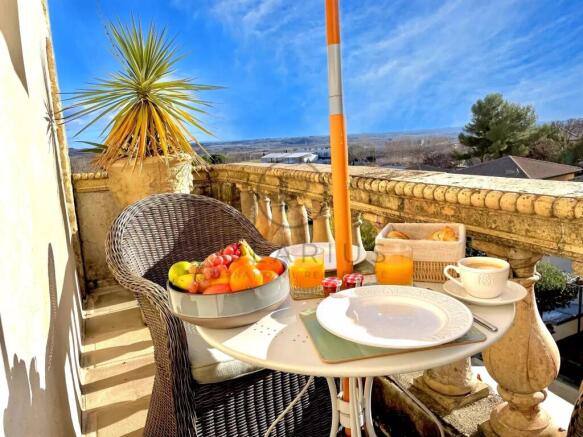 A sunny balcony with a wicker chair, a small table