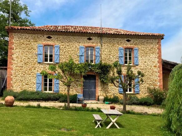 A charming stone house with blue shutters, surroun