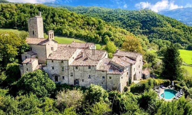 Stone buildings nestled in a lush hillside landsca