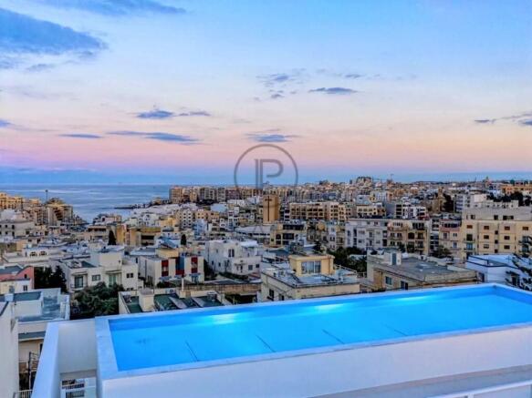 Rooftop pool overlooking a cityscape at sunset, wi