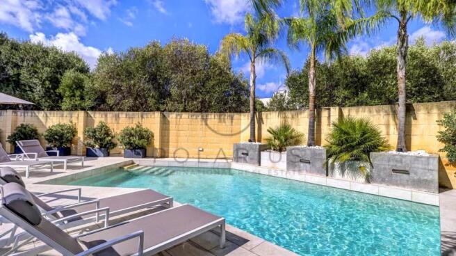 A serene outdoor pool area with lounge chairs, sur