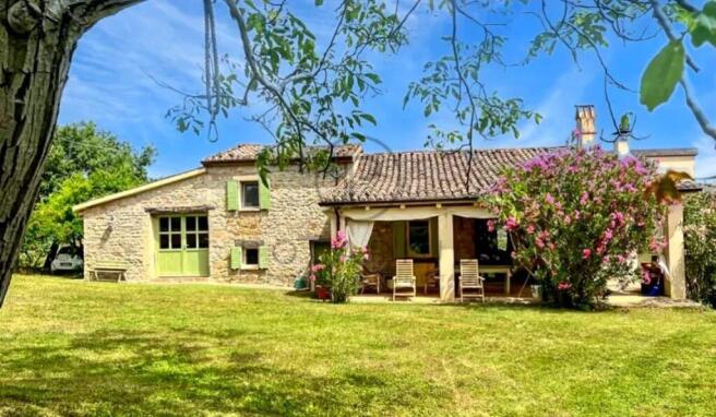 A charming stone house with a sloped, tiled roof i