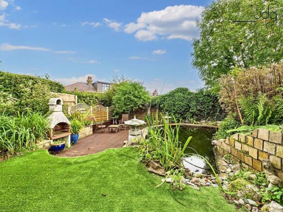 Spacious garden with a mixed of decking, artificial lawn and a pond
