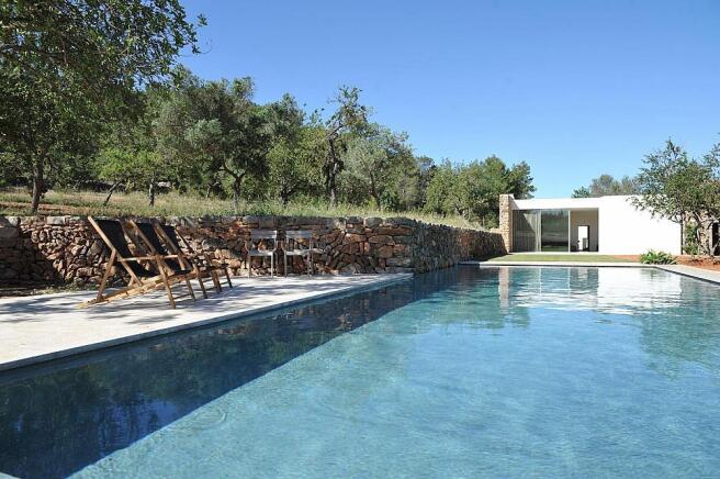 Stunning 200-year-old Ibiza finca surrounded by lush greenery and rolling hills.