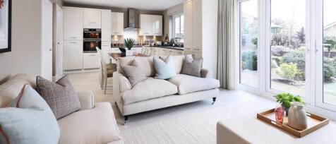 Bright, modern living room with cream sofas, cushions, and large glass doors opening to a garden in