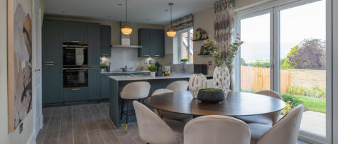 Modern open-plan kitchen and dining area with blue cabinets, beige chairs, and large sliding glass d