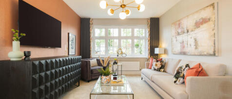 Modern living room with a beige sofa, colourful cushions, large window, flat-screen TV, and decorati