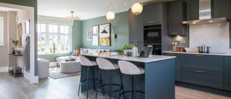 Modern open-plan kitchen and living area with green walls, grey cabinetry, a bar-style island, and a