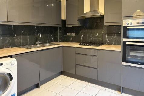 Contemporary fitted kitchen with glossy grey ca...
