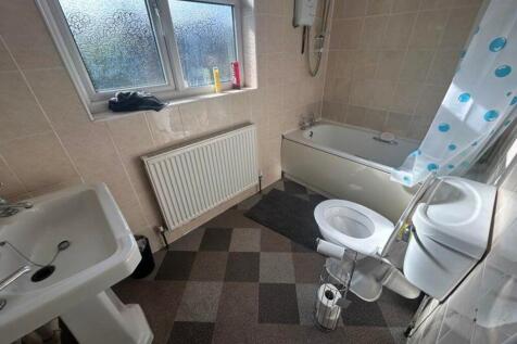 A bright and clean bathroom featuring a bathtub...