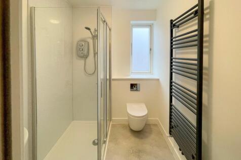 A modern bathroom featuring a sleek glass showe...
