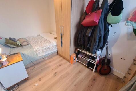 A cozy single bedroom featuring a neatly made b...