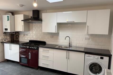Modern kitchen featuring sleek white cabinetry,...