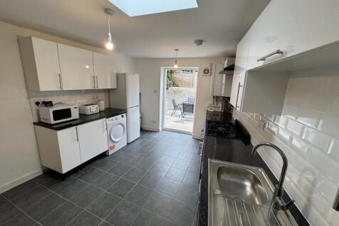 This modern kitchen features sleek white cabine...