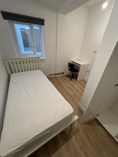 A cozy and well-lit single bedroom featuring a ...