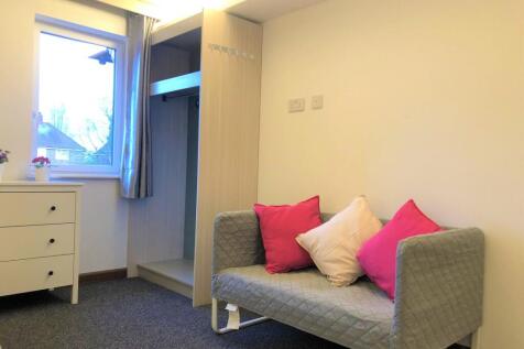 A cozy single bedroom featuring a neat gray sof...