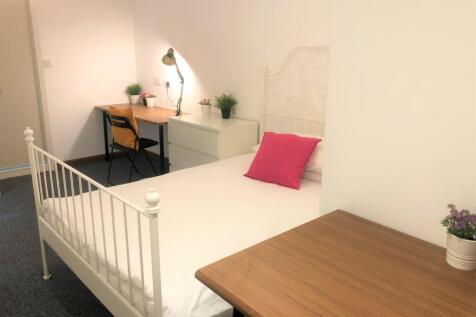 A neat and cozy single bedroom featuring a whit...