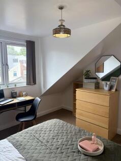 A bright and cozy single bedroom featuring a co...