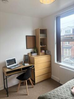 A well-kept single bedroom featuring a neat stu...