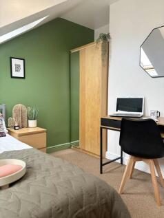 A cozy bedroom featuring a stylish green accent...