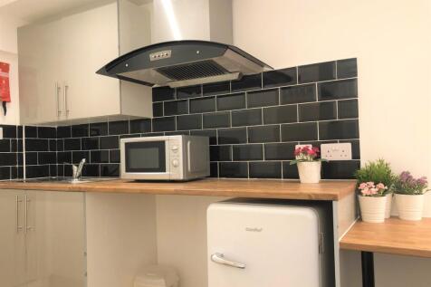 A modern kitchen featuring sleek black tiled ba...