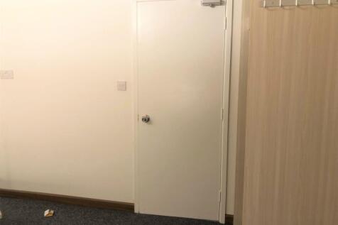 A simple hallway featuring a plain white door a...