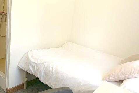 A cozy single bedroom featuring a neatly made b...