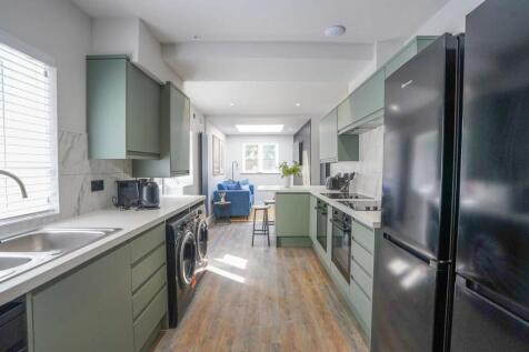 Modern kitchen featuring sleek green cabinets, ...