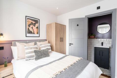 Bright, modern master bedroom featuring a large...