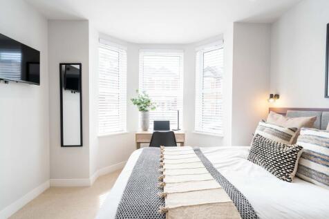 Bright and modern bedroom with large windows al...