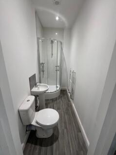 A modern bathroom featuring a curved glass show...