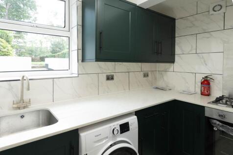 Modern kitchen with sleek dark green cabinets, ...