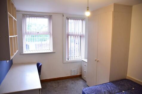 A cozy student bedroom featuring two windows wi...