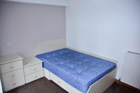 A modest bedroom featuring a single bed with a ...