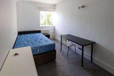 A clean and well-lit student bedroom featuring ...