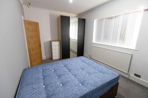 A well-lit and tidy bedroom featuring a comfort...