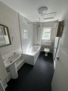A bright and clean bathroom featuring a bathtub...