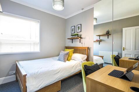 A bright and tidy single bedroom featuring a wo...