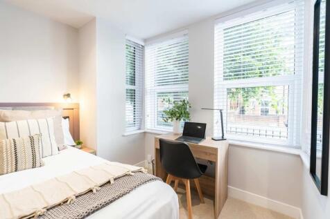 Bright and welcoming bedroom featuring a cozy b...