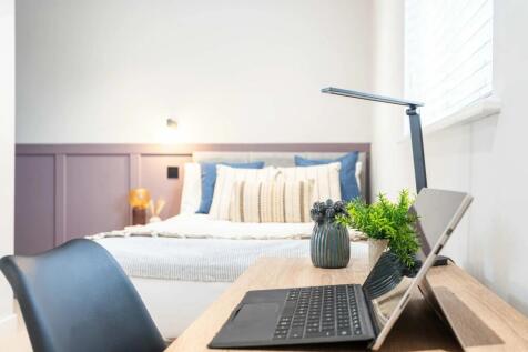 A well-lit, inviting bedroom featuring a comfor...