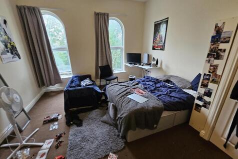 A cozy bedroom featuring a large bed, natural l...